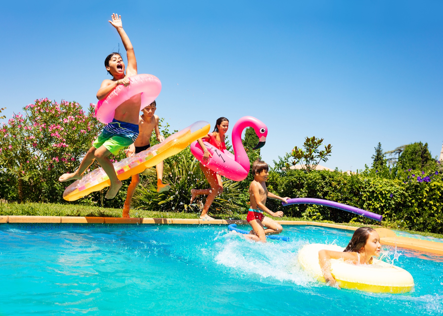 Family relaxing and swimming together in a clean backyard pool on a sunny day.